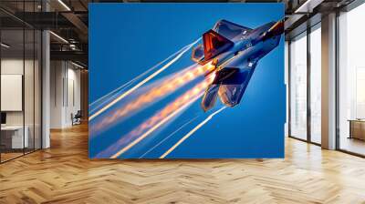 Jet fighter F-22 Raptor flying fast through the blue sky and orange glow of its engines Wall mural