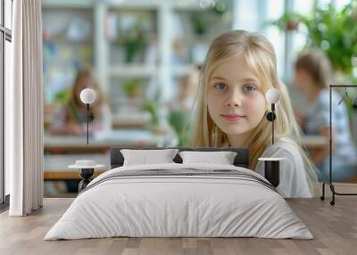 Portrait of a cute little girl sitting at a table in a classroom Wall mural