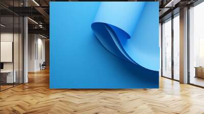 A blue paper sheet curved in a beautiful wave shape with smooth edges and different shades of blue. Wall mural