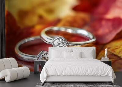 Two silver rings with diamonds on top are lying on yellow, red and orange autumn leaves. Wall mural