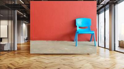 Blue plastic chair laid against the red wall. Copy space for the text. Wall mural