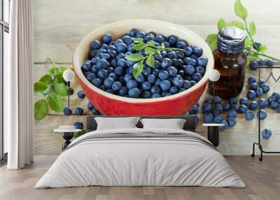 Blueberry in a red bowl with leaf on top on wooden table Wall mural