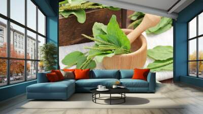 Plantain leaves in a mortar with fresh flowers and on wooden table, closeup, copy space, green medicine, diet food and drink, floral tea for lung and repiratory health concept Wall mural