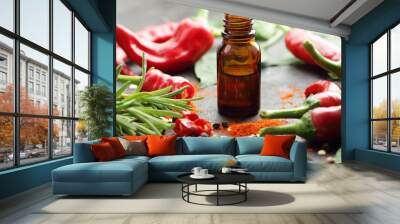 Red chili pepper oil, tincture, extract or vinegar with fresh vegetables and leaves on black table, closeup, copy space, organic spicy food, hair and body healthy care concept Wall mural