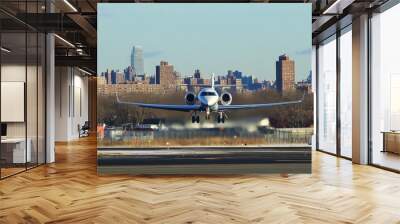 A private jet takes off from a runway with a city skyline in the background. Wall mural