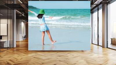 Rear view of Asian child girl holding his hands up at the beach during summer vacation, healthy lifestyle concept.  Wall mural