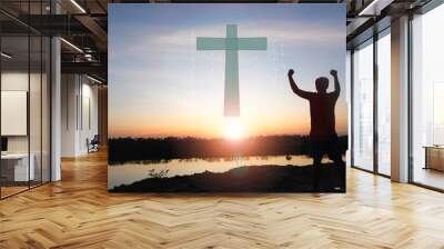 A man raises her hands and cross  with sunset.She is so calm hope,respect,spiritual , crucifix,religion and peace.Photo Christian and hope concept idea. Wall mural