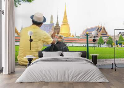 Traveler man and woman with a backpack in temple. They are siting and see The Grand Temple Palace in Bangkok. Man is pointing it.Thailand.holiday, vacation , Photo Travel and relax time concept. Wall mural