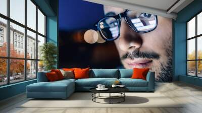 A man wearing glasses looking at the computer screen with trading charts reflecting in eyeglasses. Wall mural