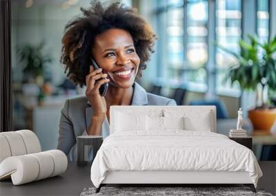 Happy black businesswoman talking on mobile phone in the office. Wall mural