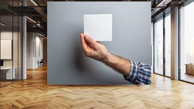 Male hand holding a square blank sheet of paper (ticket, flyer, invitation, coupon, etc.) on gray background Wall mural