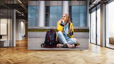 Beautiful girl uses smartphone and sits on skateboard. Wall mural