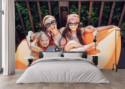 Beautiful mother with two daughters sitting on an orange lounge Wall mural