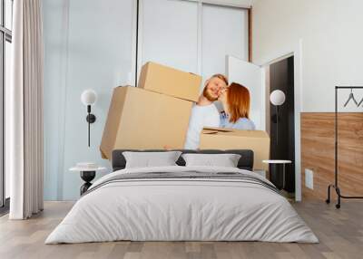 Happy couple holding cardboard boxes and moving to new place Wall mural