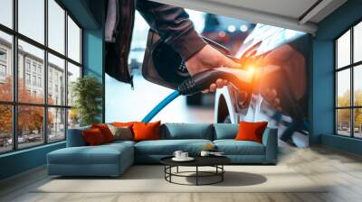 Human hand is holding Electric Car Charging connect to Electric car Wall mural