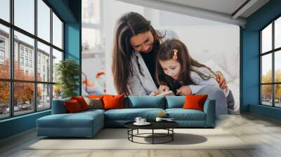 Mom and daughter are looking at the smartphone Wall mural