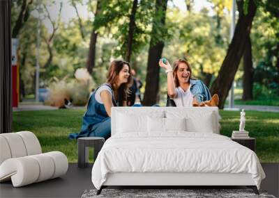 Two female friend in the park play with little dog Wall mural