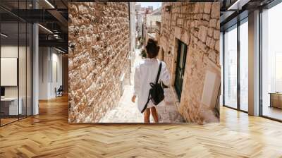 Young girl walking through ancient narrow streets on a beautiful summer day Wall mural