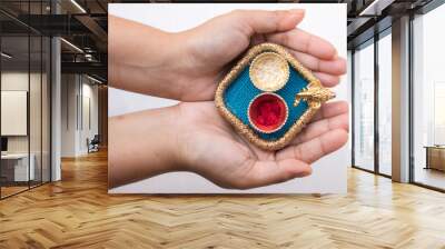 Hand holding beautiful small thali having God Ganesh face and red roli and chawal means tika and rice in white background. It is used for any hindu festival like Rakshbandhan, diwali, durga puja. Wall mural