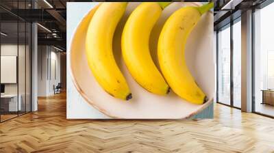 Bananas in a white dish on green pastel background. Nutrition concept Wall mural