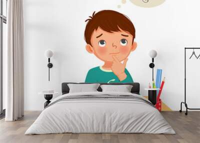 cute little boy thinking while studying and doing his homework at the desk Wall mural