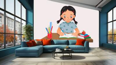 Cute little girl sitting on the desk studying writing on notebook doing her homework at home Wall mural