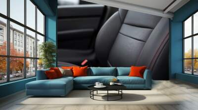 Close-up of a modern car seat featuring sleek black leather and detailed stitching, showcasing comfort and luxury. Wall mural