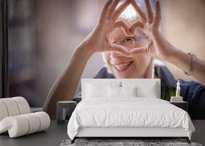 Cute senior old woman making a heart shape with her hands and fingers Wall mural