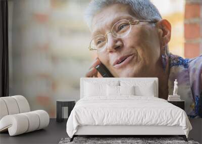 Smiling senior elderly lady having a pleasant conversation over her phone Wall mural