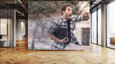 Young man running late for his meeting, looks at the time on his watch, feeling stressed and sprinting to his meeting Wall mural