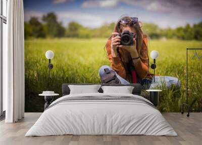 Young woman, professional photographer, taking pictures of a beautiful nature surrounding her, warm sunny day Wall mural