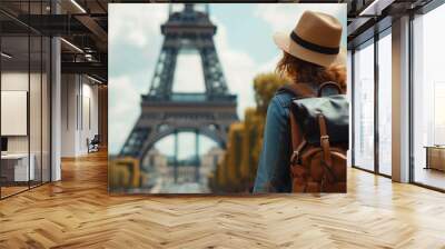 Back view of Female tourist with hat and backpack looking at eiffel tower in Paris. Wanderlust concept. Wall mural