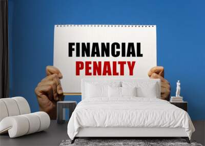 Financial penalty text on notebook paper held by 2 hands with isolated blue sky background. This message can be used as business concept about financial penalty. Wall mural