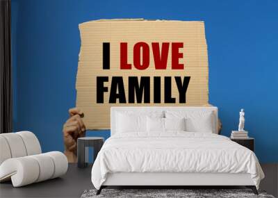 I love family text on box paper held by 2 hands with isolated blue sky background. This message board can be used as business concept about family. Wall mural