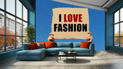 I love fashion text on box paper held by 2 hands with isolated blue sky background. This message board can be used as business concept about fashion. Wall mural