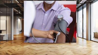 mexican nurse taking vital signs to patient wearing face mask at home Wall mural