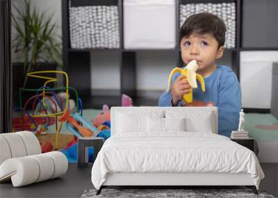 two years old mexican baby boy eating banana on messy room Wall mural