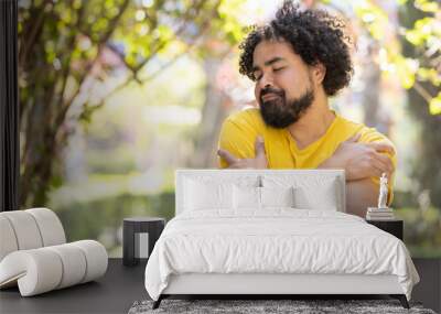 young Mexican man with beard and afro hugging himself, self love concept Wall mural