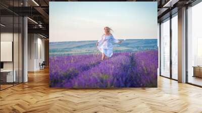 Happy woman in white dress walking in lavender field Wall mural