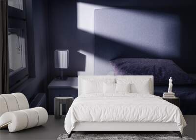 Bed at night in dark bedroom. Blue light and moonlight from window. Pillow, sheet and duvet ready for sleeping. Bedside table and nightstand. Scandinavian home interior design. Scary shade and shadow. Wall mural