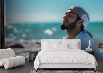 A man is laying on the beach with his head down and a scarf around his neck Wall mural