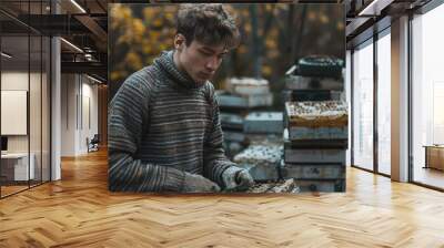 A man is sitting in front of a table with a box of yellow objects Wall mural