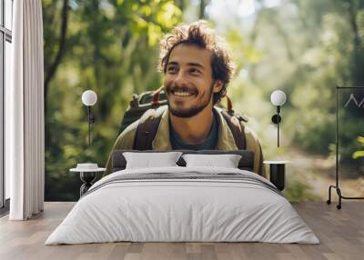 A man with a backpack and a smile on his face is standing in a forest Wall mural