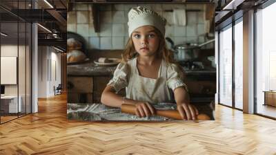 A young girl is standing in a kitchen, wearing an apron and a chef hat Wall mural