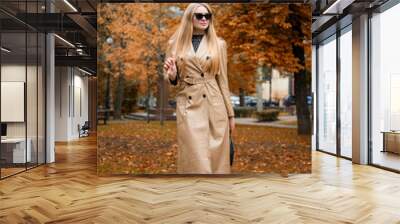  portrait of blonde woman in sunglasses  and in beige coat walking  in autumn park Wall mural