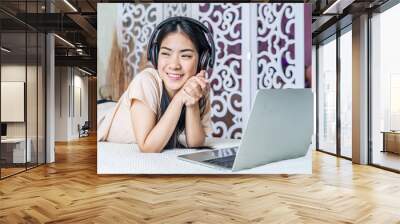 Happy young woman lying on bed, using laptop in the morning. lifestyle and relaxing at home with technology. freelancer working at home. Wall mural