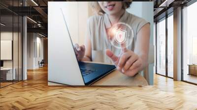 Cyber security, personal data protection, and business privacy concept. Shield and lock icon in the air while woman scanned by her finger for access identification while using laptop computer. Wall mural