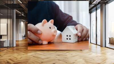 Home investment, real estate loan, savings for buy a new house, property profit management, business financial concepts. Miniature white house model and piggy bank holding by people, on wooden table. Wall mural