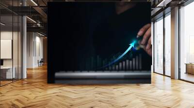 Investment technology, financial, return on investment - ROI concepts. Increasing arrow, the exponential curve of progress in business performance over charts draws by pen in hand on dark background. Wall mural