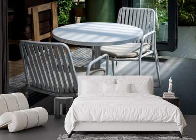 Outdoor small table set at the restaurant or cafe. Two empty chairs with pads and empty white round table in front of the coffee shop. Wall mural